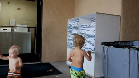 Young boy jumps to get pool towel from stack Stock Footage 94229245