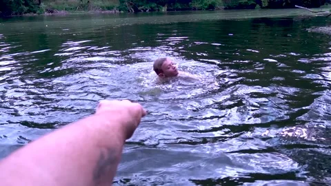 A young boy jumps from a mountain into a river Stock Footage 281716992