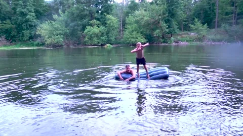 A young boy jumps from a mountain into a river Vídeo Stock 281717072