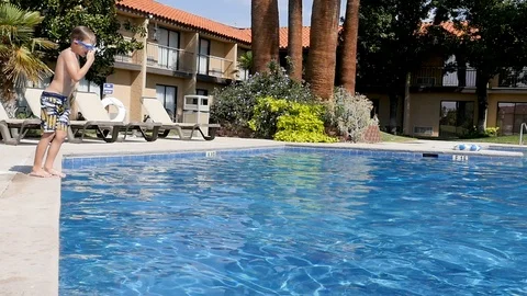 Young boy jumps into pool as camera circles Stock-Footage 94229163