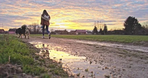 A young boy jumps into a puddle at sunset Stock Footage 145920295