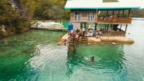 Young boy jumps into the water in the lagoon. Aerial view. Stock Footage 76325896