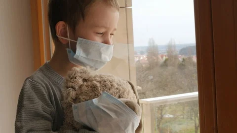 Young boy, kid, child with protective mask with teddy bead, home quarantine Vídeo Stock 126839904