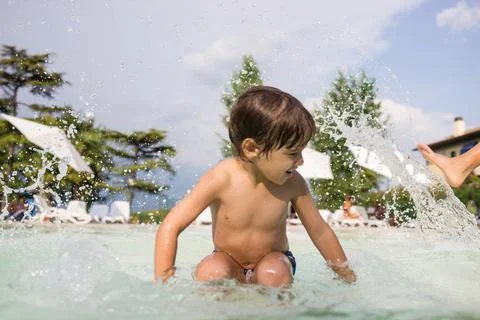 Young boy kid child splashing in swimming pool having fun leisure activity Foto stock