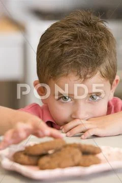 Young boy in kitchen eating cookies Stock Photos