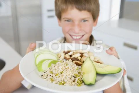 Young boy in kitchen eating rice fruit and nuts smiling Stock Photos