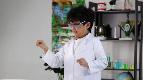 Young Boy in Lab Coat Popping Balloon During Science Experiment Video stock 338155545