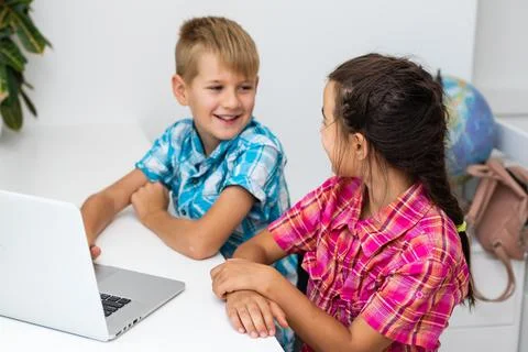 Young boy with a laptop computer sitting near a girl Stock Photos