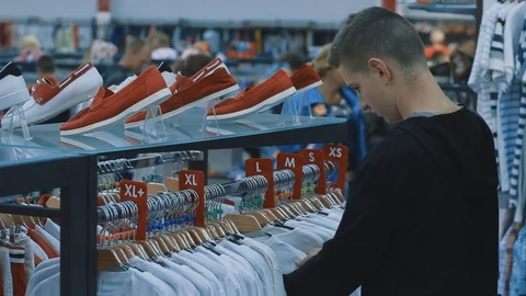 A young boy in a large store chooses new clothes for himself Stock Footage 83214990
