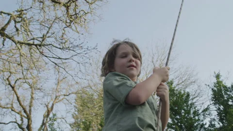 Young Boy Laughing While Swinging on a Rope Swing Outside at Golden Hour Stock Footage 208721090