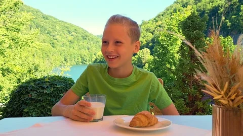 A young boy laughs while having breakfast at a scenic resort Stock Footage 317775223