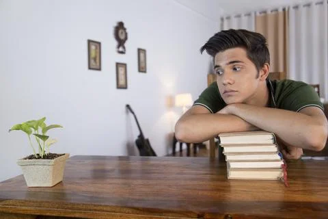 A young boy leaning on a stack of books and thinking Stock Photos