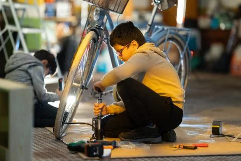 Young boy learning bicycle maintenance skills repairing tire Foto stock