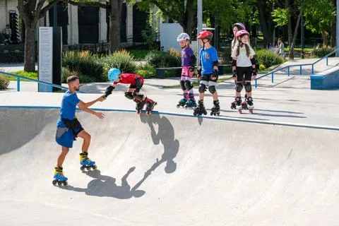 Young Boy Learning Inline Skating With Coach at Skatepark Stock Photos