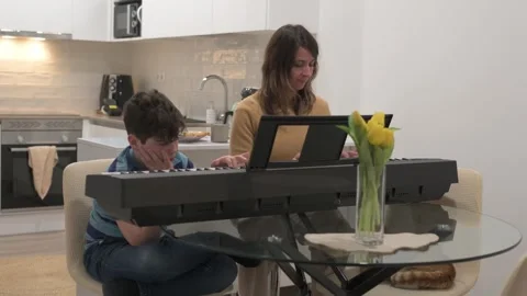 Young boy learning piano with his mother at home Stock Footage 306290452