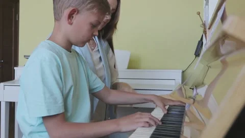 Young Boy Learning To Play Piano Having Lesson From Female Teacher Stock Footage 155375654