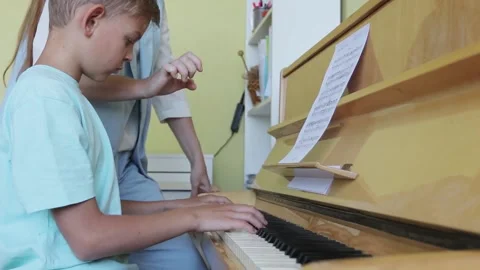 Young Boy Learning To Play Piano Having Lesson From Female Teacher Stock Footage 155484277
