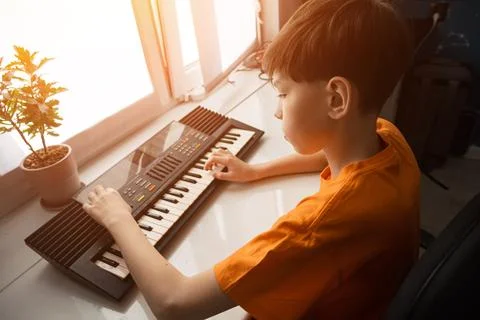Young boy learning playing electronic keyboard at home Stock Photos