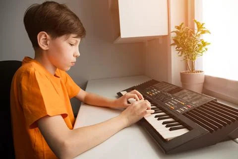Young boy learning playing electronic keyboard at home Stock Photos