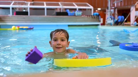 Young boy learning to swim with floating toys in indoor pool Stock Footage 313300827