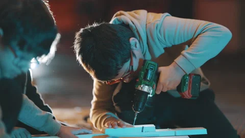 Young boy learning woodworking skills using power drill Stock Footage 329544723