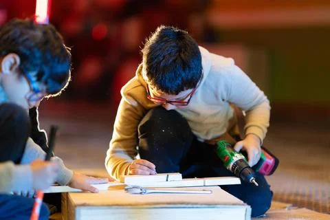 Young boy learning woodworking using power drill in workshop Stock Photos