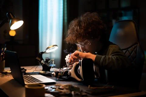 A young boy learns electronics and soldering wires on an old robot. A child Stock Photos