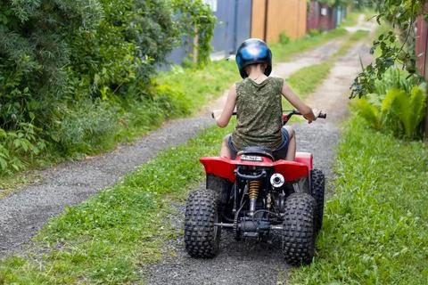 Young boy learns to ride an old refurbished children's quad bike on narrow co Stock Photos