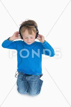 Young boy listening music through headphones Stock Photos