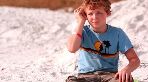 Young boy listens to ocean in seashell Stock Footage 1003229