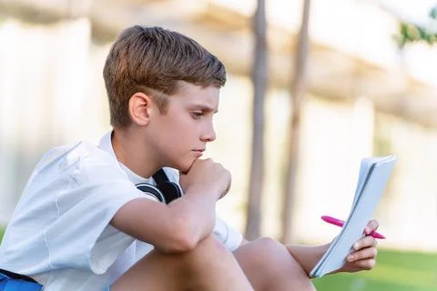 Young boy looking concentrated while doing school homework outdoors. Stock-Fotos