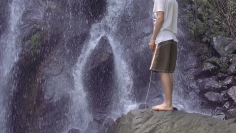 Young boy looking fascinated at waterfall wearing shorts  - Tilt up Stock Footage 127045454