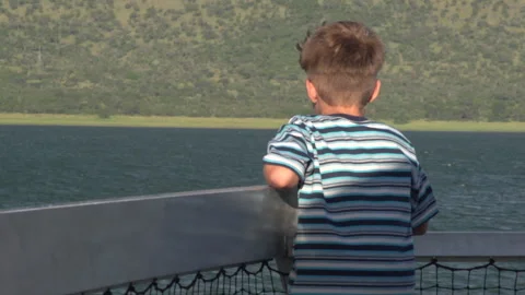 Young Boy Looking at Mountains From Cruise Ship Deck Balcony Stock Footage 338433438