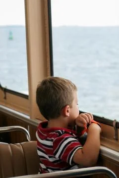 Young boy looking out the window on the ferry Stock Photos