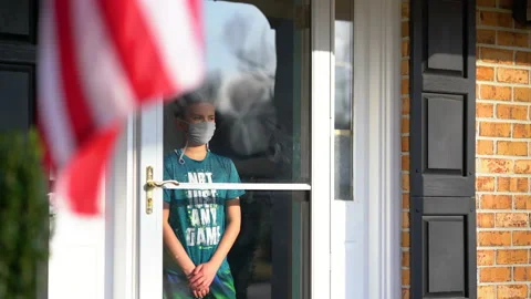 Young Boy Looking Outside Through Glass Door With American Flag Stock-Footage 149897348
