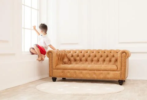 Young boy looking pensively while sitting on couch Stock Photos
