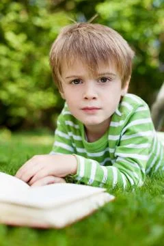 Young boy looking up from reading a book Stock Photos