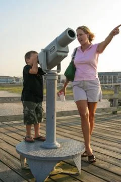 Young boy looking through telescope on the pier Stock Photos
