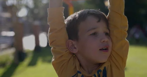 Young boy looking worried and lets go of monkey bars - close up on hands Stock Footage 320923271