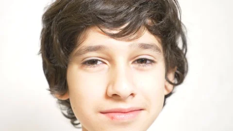 A young boy looks at the camera and smiling. 4k. the boy laid his head on his Vidéo 89489097