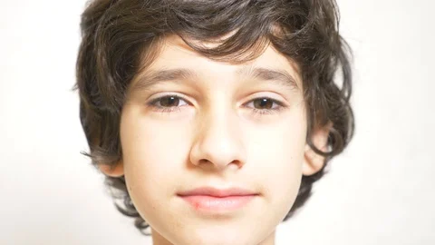 A young boy looks at the camera and smiling. 4k. the boy laid his head on his Stock Footage 89489436