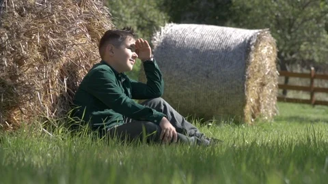 A young boy looks at the rays of the sun sitting on the grass. Stock Footage 122638812