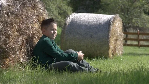 A young boy looks at the rays of the sun sitting on the grass. Stock Footage 122640290