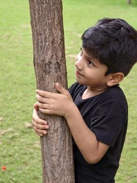 A young boy lovingly hugging a tree, showing care for nature and symbolizing env Stock Photos