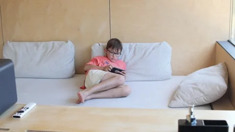 Young boy lying on a couch is using a smartphone in six consecutive frames Stock Footage 281971496