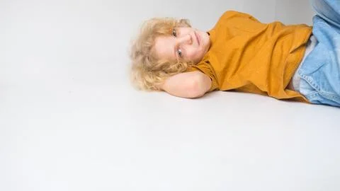 Young Boy Lying Down Casually in a Bright Studio Setting Stock Photos