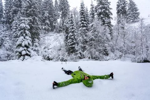 Young boy lying on the snow in forest Stock Photos