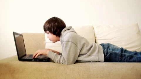 Young boy lying on sofa with laptop Stock Footage 1160480