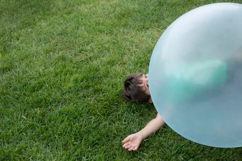 Young boy lying under large inflatable ball Stock Photos