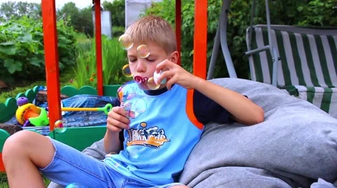 Young boy making bubbles Видео 64971479